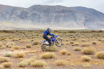 Man riding a motorcross bike in the steppes of Mongolia, on the hills of Mongolia