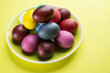 Colorful Easter eggs as an attribute of Easter celebration on the yellow plate.