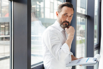 Photo of bearded handsome businessman examining documents