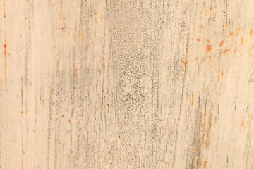 Old rusty metal wall covered with beige cracked peeling paint with spots of rust. Abstract modern trendy texture background