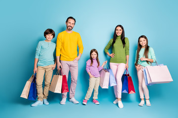 Full length body size view of nice attractive lovely charming glad friendly cheerful family carrying bags new clothes spending day daydream isolated on bright vivid shine vibrant blue color background