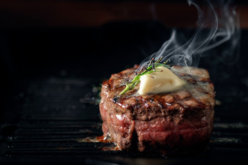 A steaming beef tenderloin steak is grilled in a grill pan with the text copy space. The concept of the recipe , filet Mignon - obrazy, fototapety, plakaty