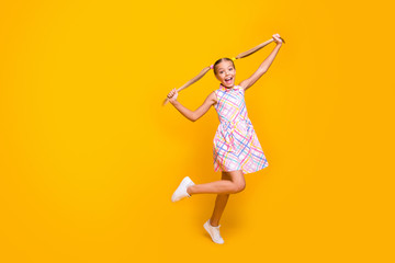 Full body photo of beautiful little lady good mood hold raise pretty long tails playful girl walk street wear plaid summer dress sneakers isolated yellow vibrant color background