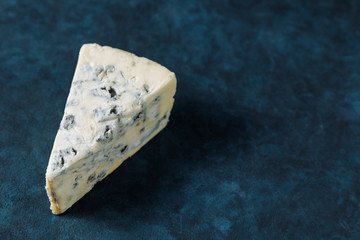 Blue cheese on a dark textured background. Top view with free text space