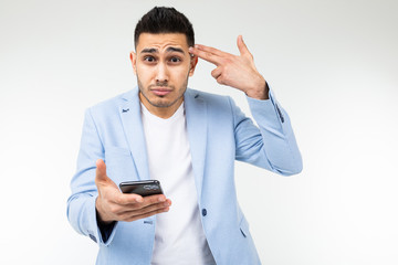 businessman twists at his temple and is surprised with information on the Internet holding a phone in red on a white background studio with copy space