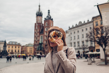 Tourist woman holding bagel obwarzanek traditional polish cuisine snack on Market square in Krakow. Travel Europe