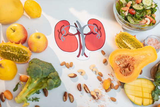 Human kidneys drawing with variety of healthy fresh fruits and vegetables on the table. Concept of balanced nutrition for kidneys health