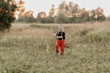 little boy running on grass and smiling in summer field