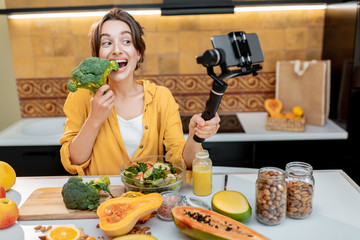 Young and cheerful woman vlogging on mobile phone about healthy food and cooking. Concept of healthy eating and social media influencing