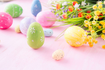 Easter eggs with wild flowers on a wooden pink table background