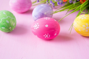 Easter eggs with wild flowers on a wooden pink table background
