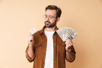 Concentrated unshaved man holding money and credit card.