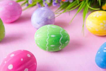 Easter eggs with wild flowers on a wooden pink table background