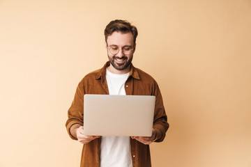 Optimistic young unshaved man using laptop computer.