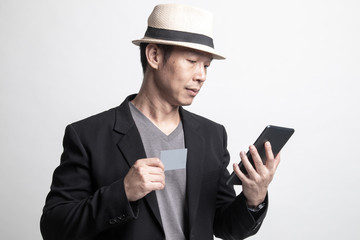 Adult Asian man is shopping online with credit card and tablet.