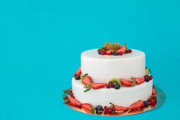 Cake with fresh berries on blue background copy space