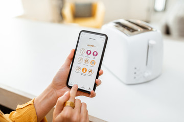 Controlling smart kitchen appliance using mobile phone at home, close-up on mobile screen. Concept...