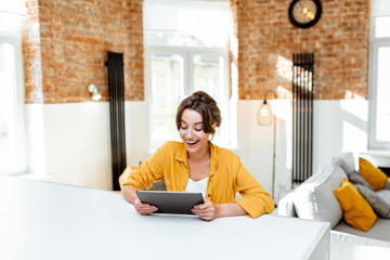 Young and cheerful woman using a digital tablet while sitting relaxed at home. Concept of a leisure activities with mobile devices at home © rh2010