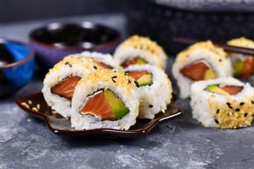 Inside out California roll sushi filed raw salmon fish, avocado, cream cheese and topped with...