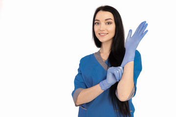 Woman doctor in blue uniform puts on gloves