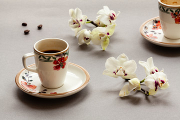 Coffee in small Italian porcelain cup with floral pattern. Another empty cup (drunk coffee) in...