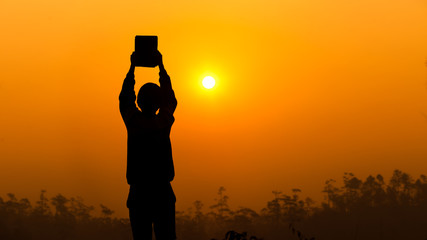 Human holding and lift the Bible up with light sunset background, christian silhouette concept.