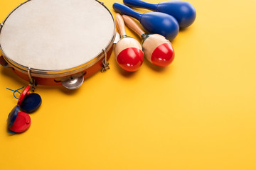 Wooden colorful and blue maracas with tambourine and castanets on yellow background