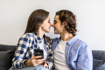 Young couple or marriage sharing a smart phone to watch media content sitting on a couch at home