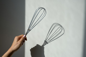 Hand holding balloon whisk mixing for kitchen cooking on white background