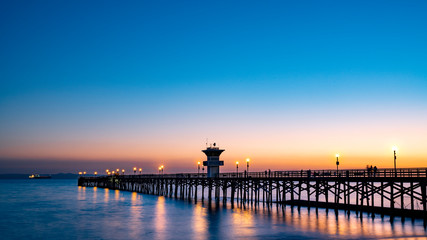 Beautiful Seal Beach Pier at sunset; peaceful water and wooden bridge