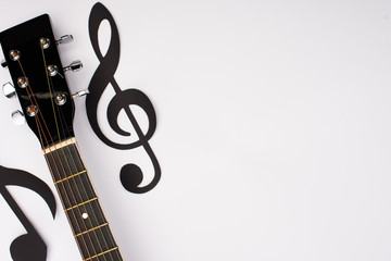 Top view of paper cut music notes and acoustic guitar on white background