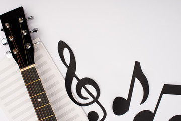 Top view of paper cut notes near music book and acoustic guitar on white background