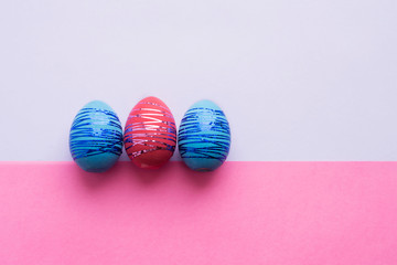 Three easter eggs on paper color background. Easter holiday concept.