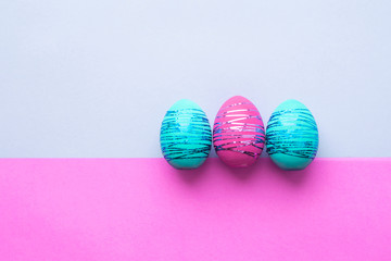 Three easter eggs on paper color background. Easter holiday concept.