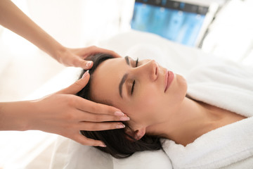 Fototapeta na wymiar Dark-haired woman feeling relaxed while having facial massage