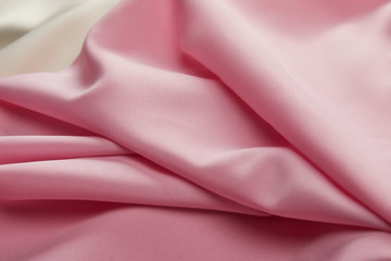 close up view of satin pink and white soft and wavy fabric