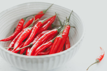 Chili peppers in a white ceramic bowl on a table. Close up view.