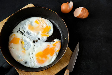 scrambled eggs eggs in a frying pan, shell on a black background