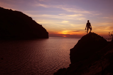 Silhouette of photographer using camera on the top of a rock by the sea , Twilight  sky sunset