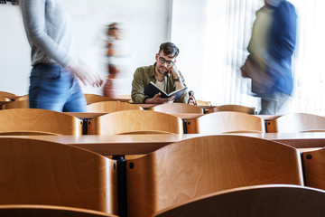 Young male student taking a test in university classroom