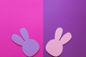 Fototapeta na wymiar A pink and purple background with pink and purple Easter bunnies. There is room for your text above the bunnies.