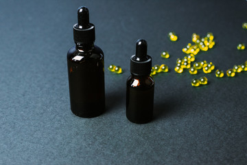 Moisturizing and healing skin serum with vitamin C on a black background. Vitamin capsules as a supplement to a cream or essence for home care