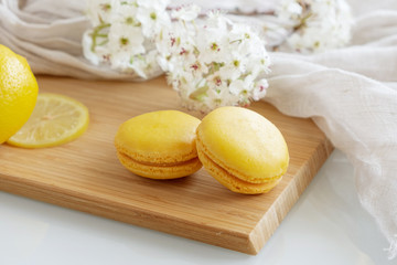 Lemon macarons with white flowers on white background