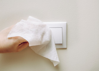 Close up view of woman hand using antibacterial wet wipe for disinfecting home room electric switch...