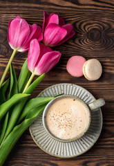 pink tulips, cup with coffee and macaroons on a wooden background, copy space