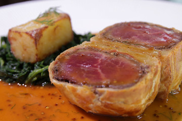 Fillet Wellington in puff pastry with Spinach and fried potatoes.Close up
