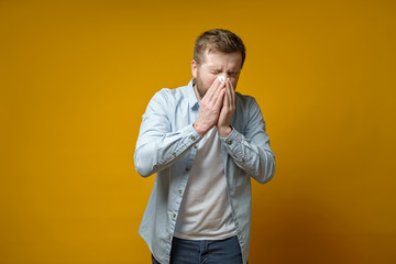 Man is sick, has a runny nose, he coughs or sneezes, covering mouth with a handkerchief. Concept of...