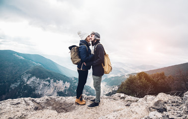 Beautiful couple of hikers in love are kissing on the top of the mountain on a amazing landscape at...