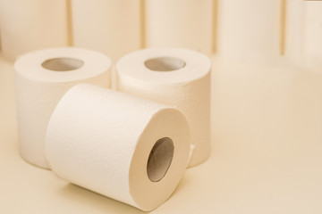 Three paper rolls and pile of toilet paper rolls on background. Stocking up concept
