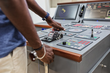 Captain's hands at the helm of a boat.
